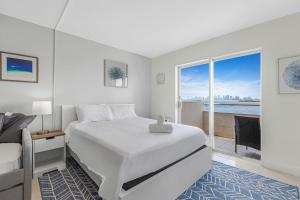 a white bedroom with a bed and a balcony at Waterfront Studio Condo in the Heart of Miami - Skyline & Bay Views in Miami Beach