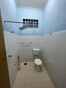 La salle de bains blanche est pourvue de toilettes et d'une fenêtre. dans l'établissement Relaxs Homestay Semi-D, à Bachok