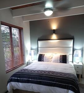 a bedroom with a large bed and two windows at Crest Farm Cottage in Waterfall