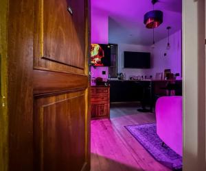 um quarto com iluminação roxa e uma porta de madeira em Flamant Rose em Annecy