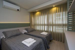 a bedroom with two twin beds and a window at Apto Luxo Vila di Tondo Area Lazer na Cobertura in Bento Gonçalves