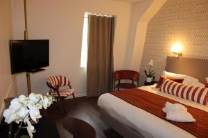 a hotel room with a bed and a flat screen tv at Hôtel La Truffe Noire in Brive-la-Gaillarde