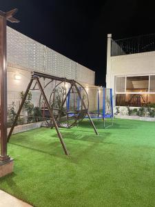 un parque infantil en un patio con césped verde en شاليهات وجدان الهدا, en Al Hada