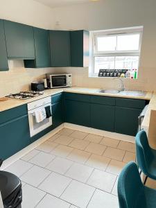 uma cozinha com armários verdes e um lavatório em Grey Eagle Apartments Shoreditch em Londres