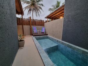 uma piscina com duas cadeiras num quintal em Vila Manguezal, 2 suítes com opção de piscina e sauna integrada privativas na rota ecológica dos Milagres em Pôrto de Pedras
