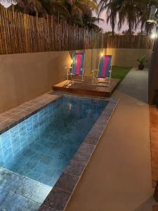 a swimming pool with two chairs in a backyard at Vila Manguezal, 2 suítes com opção de piscina e sauna integrada privativas na rota ecológica dos Milagres in Pôrto de Pedras