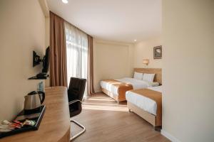 a hotel room with two beds and a desk at Atrium Boutique Hotel in Tbilisi City