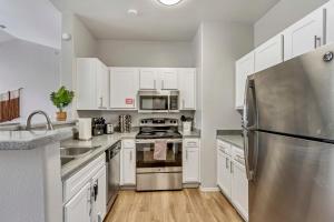 una cucina con armadi bianchi e frigorifero in acciaio inossidabile di Quiet Apartment Central to Davis County a Clearfield