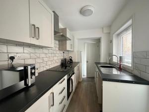 uma cozinha com armários brancos e bancadas pretas em Waterloo Street em Kings Lynn