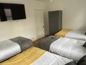 a room with three beds and a flat screen tv at Hometel Large Luxurious Comfy Home Can Sleep 16 in Thornton Heath