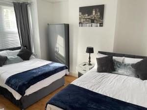 1 dormitorio con 2 camas, lámpara y ventana en Hometel Large Luxurious Comfy Home Can Sleep 16, en Thornton Heath