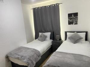 1 Schlafzimmer mit 2 Betten und einem Fenster in der Unterkunft Hometel Large Luxurious Comfy Home Can Sleep 16 in Thornton Heath