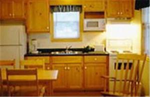 a kitchen with wooden cabinets and a sink at Cabot Trail Sea & Golf Chalets in Chéticamp