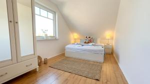 a white bedroom with a bed and a window at Haus Eversand Nr 2 in Cuxhaven