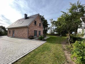 a brick house with a grass yard next to a driveway at Ferienhaus Libelle für 14 Personen - Haupthaus und Nebenhaus in Rankwitz