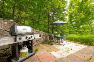 - un barbecue extérieur avec une table et un parasol dans l'établissement Chalet Village Ski & beach by Ma Kabane, à Saint-Adolphe-d'Howard