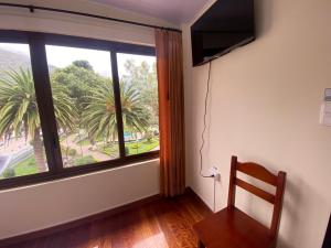 Cette chambre dispose d'une fenêtre avec une chaise et d'une télévision. dans l'établissement Hostal Magdala, à Baños