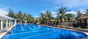 una gran piscina con palmeras en el fondo en Blue Shell Resort, en Mui Ne