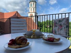 una mesa con dos platos de comida y una torre del reloj en Schloss Hürbel Storchennest-Appartement - Luxury Apartment THE Stork Nest, en Gutenzell-Hürbel