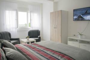 a bedroom with a bed and two chairs and a window at Meli apartman in Smederevo