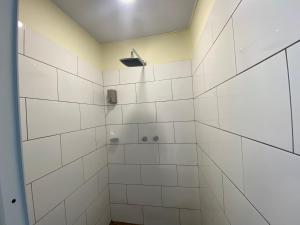 a bathroom with a shower with white tiles at Hostal Magdala in Baños