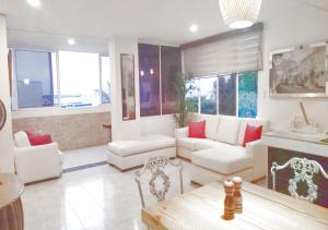 una sala de estar con muebles blancos y almohadas rojas. en Apartamentos Commodore Bay Club, en San Andrés
