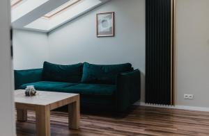 ein Wohnzimmer mit einem grünen Sofa und einem Tisch in der Unterkunft APARTAMENTY PRZY PARKU- Parking GRATIS!!! in Częstochowa