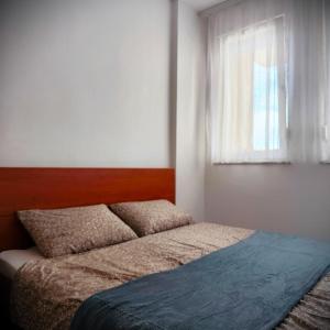 uma cama num quarto com uma janela em Central Park Apartment em Pristina