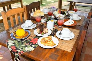 una mesa de madera cubierta con platos de desayuno en Pousada Coco Brasil, en Caraíva
