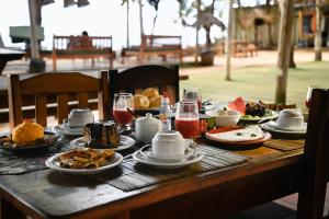 a wooden table with food and drinks on it at Pousada Coco Brasil in Caraíva