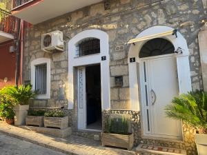 uma casa de pedra com uma porta branca e algumas plantas em Dory’s House em Ragusa