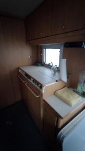 cocina pequeña con fogones y ventana en Wildcamp Resort Masseria la Murgia Unterkunft in einem Wohnwagen, en Rimbach