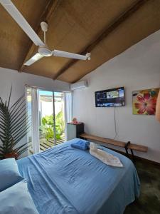 a bedroom with a blue bed and a flat screen tv at Saona lodge in Mano Juan