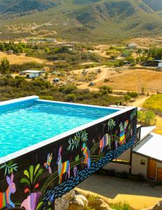 a swimming pool with a mural on the side of a building at Origen75 Loft - Villas - Skypool - Viñedo, Valle de Guadalupe in Valle de Guadalupe