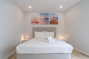 Un dormitorio con una cama blanca con un animal de peluche. en Buzz Apartment, en Jardim do Mar