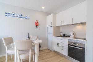 a kitchen with white cabinets and a table and chairs at Buzz Apartment in Jardim do Mar