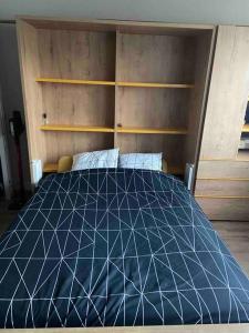 Schlafzimmer mit einem Bett mit einer schwarzen und weißen Bettdecke in der Unterkunft Studio de 28 m2 lumineux et élégant in Chambéry