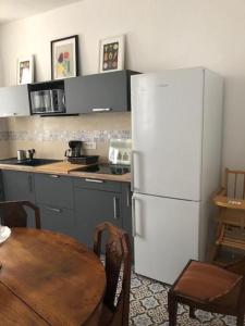 サリー・ド・ベアムにあるMaison ICHABELENIAのテーブルと白い冷蔵庫のあるキッチン