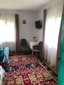 ein Wohnzimmer mit einem Tisch und einem Teppich in der Unterkunft Pridvorul lui Viorel in Proviţa de Sus