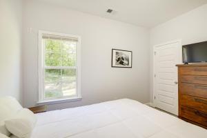 a white bedroom with a bed and a television at Sunny Memphis Home about 2 Mi to Beale Street! in Memphis