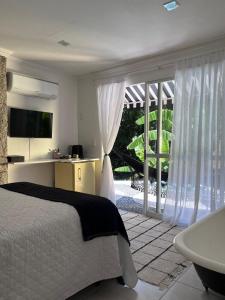 a bedroom with a bed and a tub and a window at CasaIvan in Florianópolis