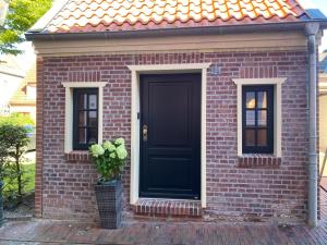 ein Backsteinhaus mit einer schwarzen Tür und einer Topfpflanze in der Unterkunft Lüttje Huus Emden in Emden