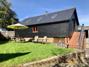 a house with a table and chairs and an umbrella at Holsworthy Holiday Cottages in Holsworthy