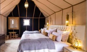 a bedroom with a large bed in a tent at Merzouga bivouac star in Taouz