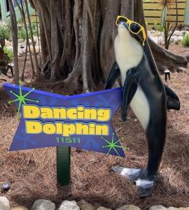 a penguin holding a sign in front of a tree at Dancing Dolphin home in Captiva