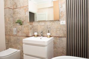 a bathroom with a sink and a toilet and a mirror at La Stejari Deluxe Apartment in Suceava