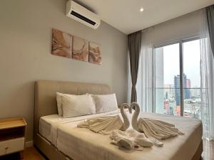 Dois cisnes estão sentados numa cama num quarto. em Quill Suites KLCC em Kuala Lumpur