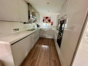 a kitchen with white cabinets and a wooden floor at Bourton House Windrush Lake in South Cerney