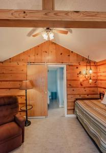 Schlafzimmer mit Holzwänden, einem Bett und einem Deckenventilator in der Unterkunft Big Blue Lake Cottages, LLC - Cottage #1 in Holton