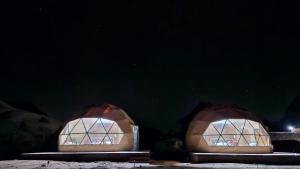 two domed buildings with windows in the dark at مخيم الجبال البرونزية in Wadi Rum